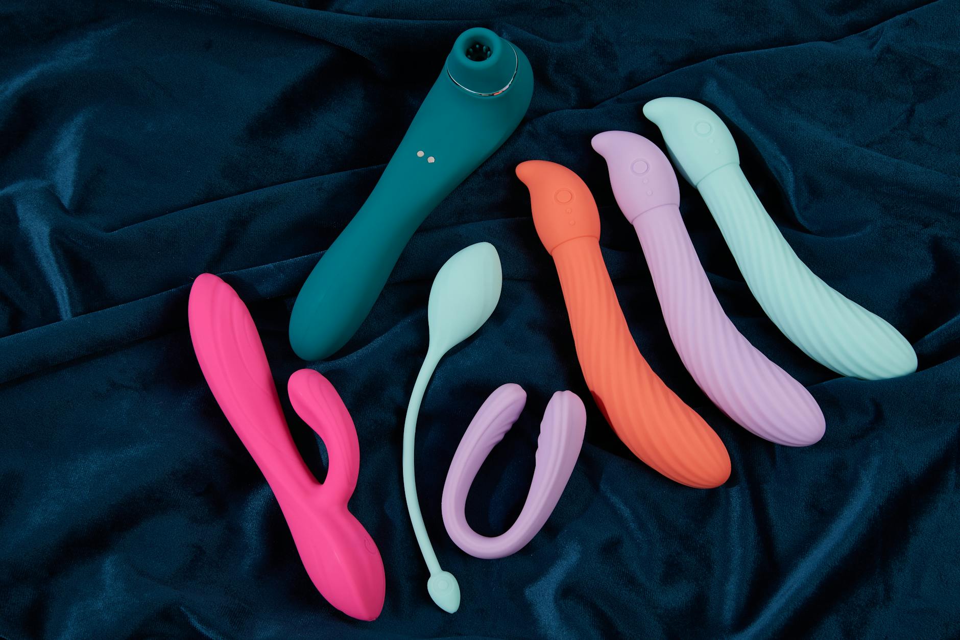 Pink vibrator on purple background with heart confetti and candles for romantic intimacy