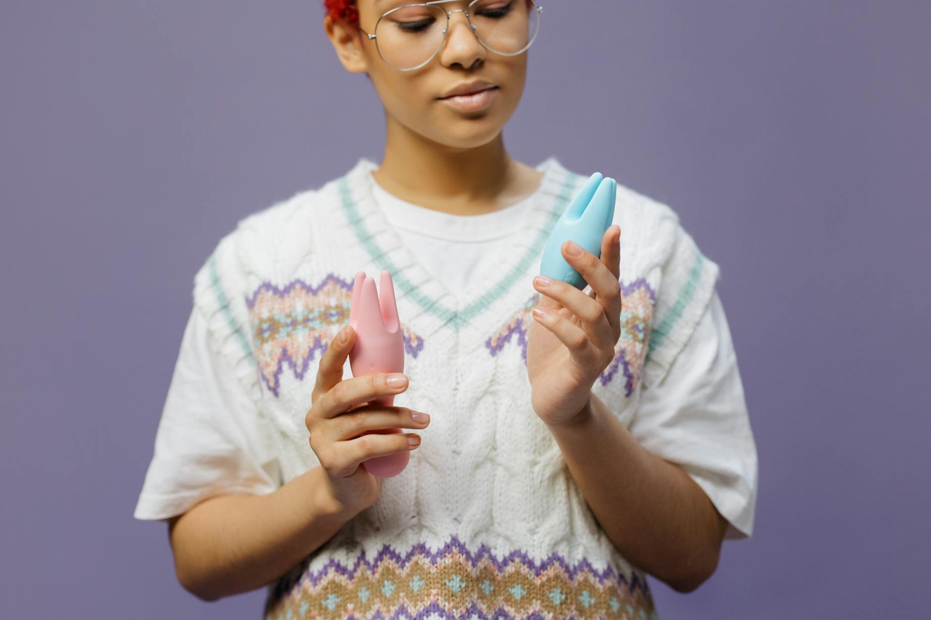 Woman holding colorful silicone vibrators, contemplating pleasure and self-care options